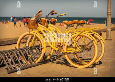 A pair of bicycles parked on the boardwalk next to the beach in Ocean City, Maryland, USA. Bikes, often called 'beach cruisers,' are a popular way to  Stock Photo