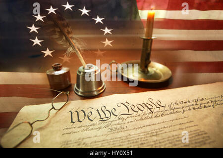 US Constitution with quill pen, ink, glasses, candle and flag with thirteen stars Stock Photo