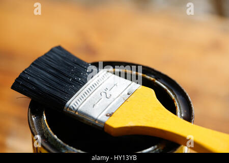 Brush resting on a tin can of protective paint for wood treatment against weathering, insects and fungus. Outdoor protection, carpentry, hard at work, Stock Photo