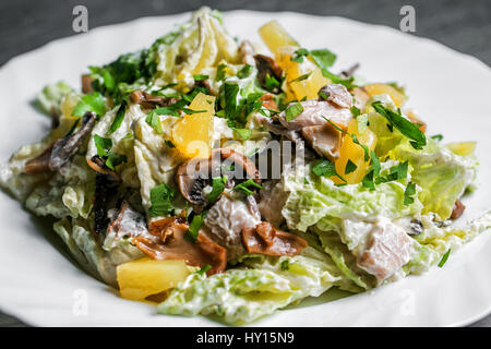 salad with mushrooms and oranges on white plate. selective focus Stock Photo