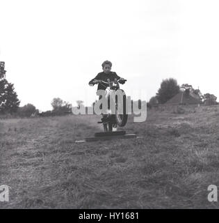 1960s, historical, young lad in a grassy field on a motorcross bike practising his technique for going over a hump or obstacle, England. Stock Photo
