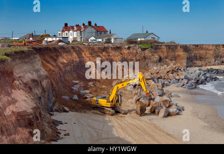 Excavator with grapple used for building sea defences at Happisburgh, Norfolk, UK, March. Stock Photo
