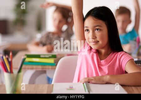 Teenage student raising hand in classroom Stock Photo