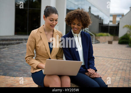 Two businesswomen using laptop in the office premises