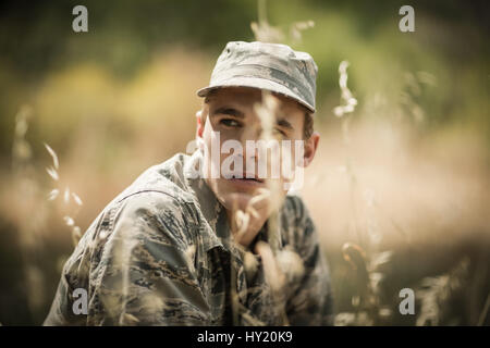 Thoughtful military soldier relaxing in grass in boot camp Stock Photo