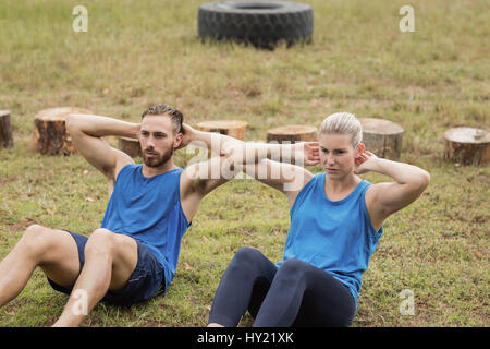 Fit people performing crunches exercise in boot camp Stock Photo