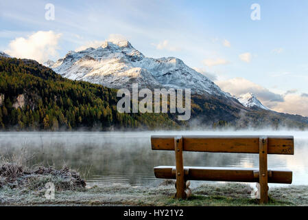Einsame Bank in einer Herbstlandschaft am Silser See mit dem Blick auf den Piz Margna, Oberengadin, Schweiz | Lonely bench in a frosty Autumn landscap Stock Photo