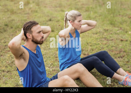 Fit people performing crunches exercise in boot camp Stock Photo