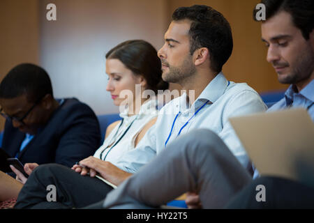 Business executives participating in a business meeting using electronic devices at conference center Stock Photo