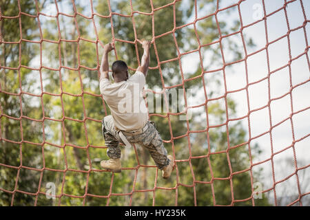 Military soldier climbing net during obstacle course in boot camp Stock Photo