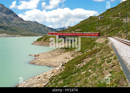 Zug der Rhaetischen Bahn am Lago Bianco am Bernina Pass in den schweizer Alpen, Schweiz.  Alpine train at Lago Bianco at the Bernina Pass in the Swiss Stock Photo