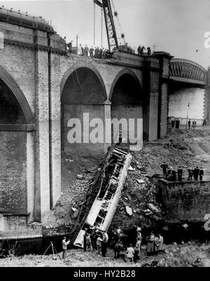 Aug. 16, 1953 - 10 Killed And 60 Injured In Train Crash At Manchester: Ten people were killed and more than 60 injured when two trains collided head-on yesterday on the Irk Valley Viaduct, about a mile from Victoria Station, Manchester. The engine and two coaches of a steam train and three coaches of an electric train were derailed. A steel coach of the electric train tore a 30 ft. gap in the wall of the viaduct and plunged 80 ft. into the river. It landed on its side and some passengers were thrown into the water. Many were trapped in the wreckage. Photo shows Rescue workers removing some of  Stock Photo