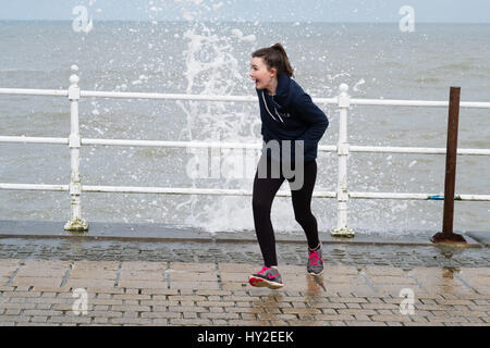 Aberystwyth Wales UK, Saturday 01 April 2017 UK weather : On the first day of April, a young girl on the promenade in Aberystwyth enjoys dodging the waves on a morning of warm sunshine and April showers of rain photo Credit: keith morris/Alamy Live News Stock Photo