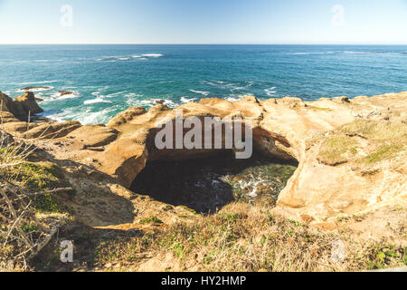 Sunny summer day at Devil's Punch Bowl State Park near Newport, Oregon, USA. Ocean waves and sunny blue sky above. Stock Photo