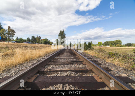 Wood and steel tracks under a deep blue sky with white clouds. Stock Photo