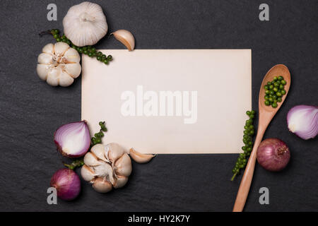 Vegetable recipe. Open menu book with fresh herbs and spices on dark background Stock Photo