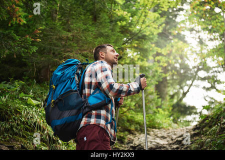 Hiker admiring the view while walking up a forest trail Stock Photo