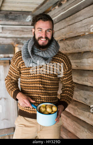 Sweden, Portrait of young man holding pot of potatoes Stock Photo