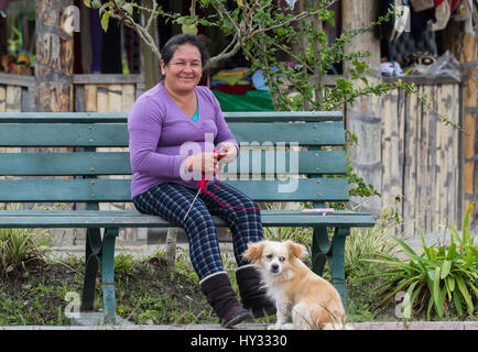 An old lady knitting on a chair with her dog in a local park. Peru. Stock Photo