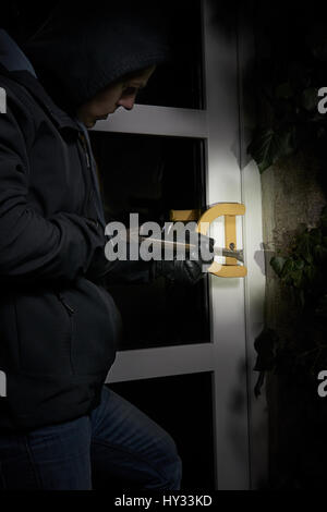 burglar trying to get into a house using a crowbar. Stock Photo