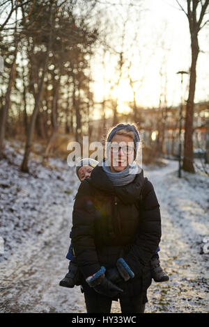 Sweden, Sodermanland, Stockholm, Johanneshov, Hammarbyhojden, Laughing mid adult woman carrying son (2-3)