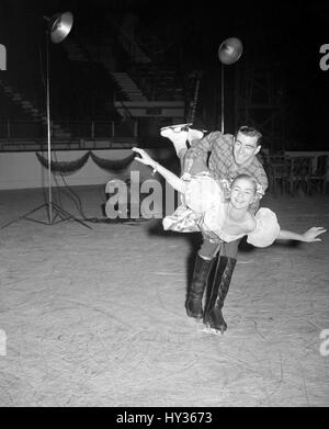 Mike Kirby, Canadian ice champion, sweeps Barbara Ann Scott, former world amateur ice figure-skating champion, off her ice-skates during rehearsals for the new show 'Rose Marie on Ice', opening at Harringay, London, on 4th July. Stock Photo