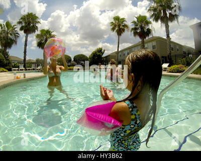 family playing with beach ball in pool Stock Photo