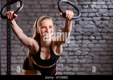 Workout on crossfit rings. Fitness woman workout on the TRX in the gym. Stock Photo
