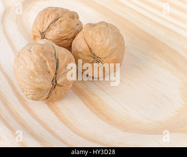 Three whole walnuts on the wooden background Stock Photo