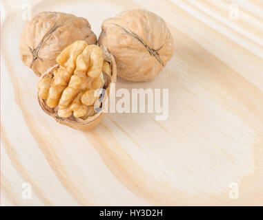 Two whole and one broken walnuts on the wooden background Stock Photo