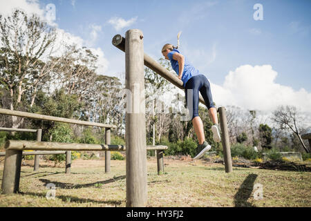 Woman jumping over the hurdles during obstacle course in boot camp Stock Photo