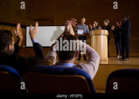 Business executives actively applauding in conference center Stock Photo