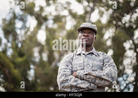 Thoughtful military soldier standing with arms crossed in boot camp Stock Photo