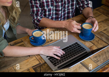 Cropped image of couple using laptop while having coffee in cafeteria Stock Photo