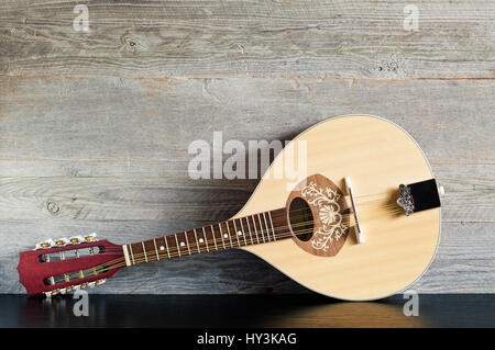 Front view of a reclined wooden flatback mandolin on a black table with a weathered wood background Stock Photo