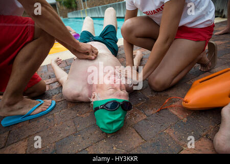 High angle view of lifeguards helping senior man at poolside Stock Photo