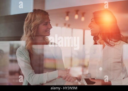 Happy businesswomen shaking hands in office Stock Photo
