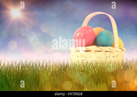 Easter eggs in wicker basket against glowing background Stock Photo