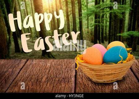 Happy easter logo against tall trees growing in forest Stock Photo