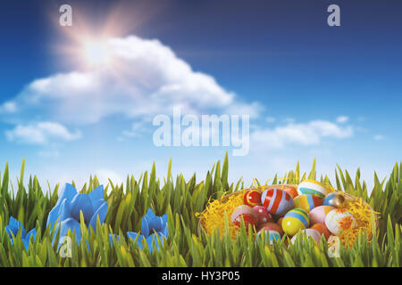 Multi colored easter eggs in wicker basket against bright blue sky with clouds Stock Photo