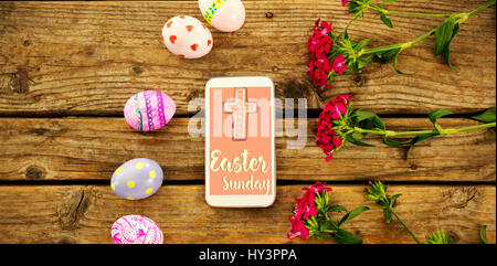illustration templates all against smartphone amidst painted easter eggs and flowers on table Stock Photo