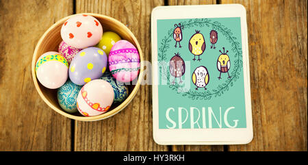 illustration templates all against painted easter eggs in bowl by digital tablet Stock Photo