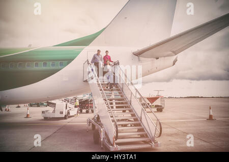 People disembarking from airplane at runway Stock Photo