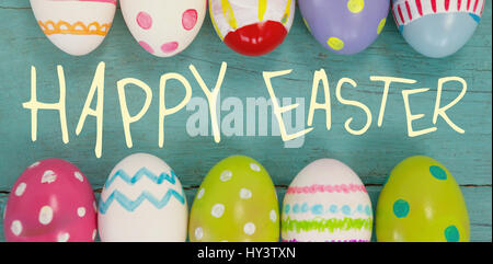 Easter greeting against various easter eggs arranged on wooden surface Stock Photo