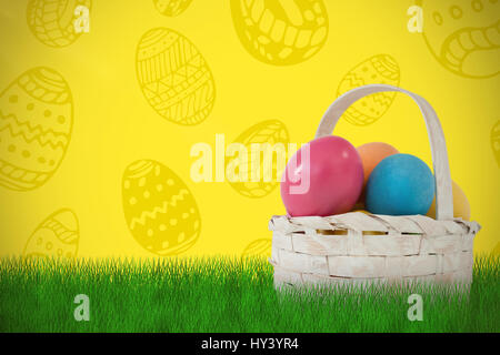 Easter eggs in wicker basket against yellow background Stock Photo