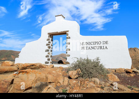 Traditional municipality sign (white arch gate) near Betancuria village with desert landscape in the background, Fuerteventura, Canary Islands, Spain Stock Photo