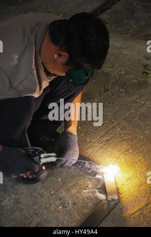 welder man welding steel on cement floor with spread spark and lighting around Stock Photo