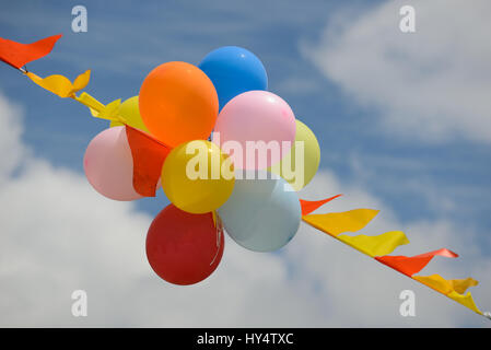 Colourful balloons and bunting against a cloudy background Stock Photo