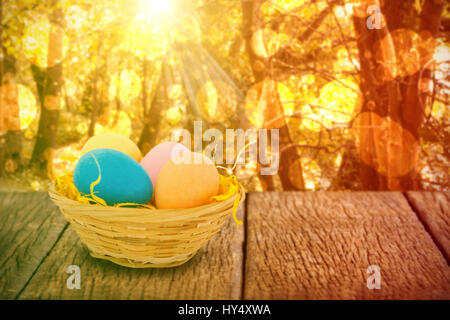 Colorful Easter eggs in wicker basket  against tranquil autumn scene in forest Stock Photo