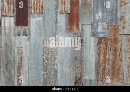Grungy background of a corrugated steel wall with rusty spots on an old building Stock Photo